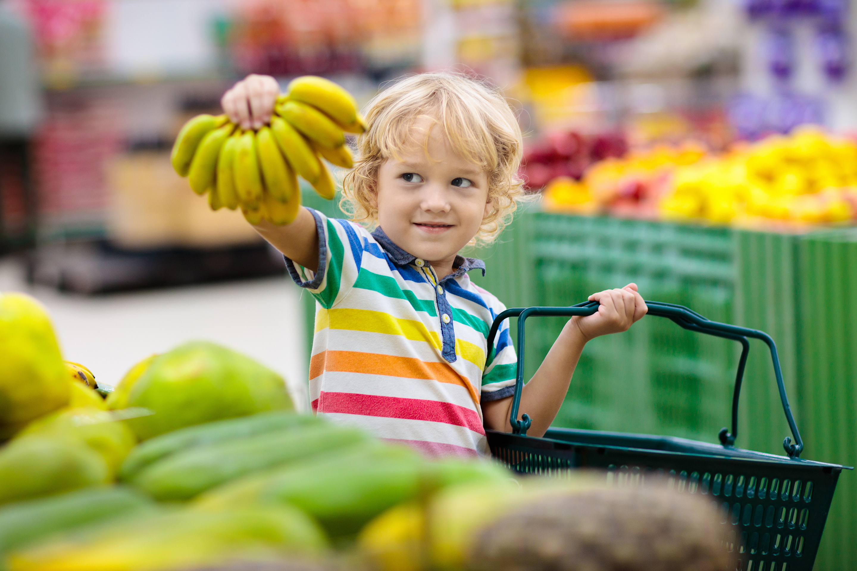 Criança escolhendo bananas no mercado